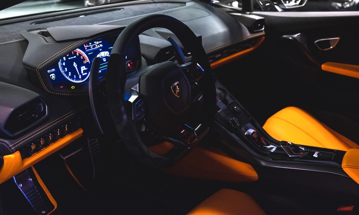 The cabin of a Lamborghini Huracan in tan leather, lit only by its instrument display.