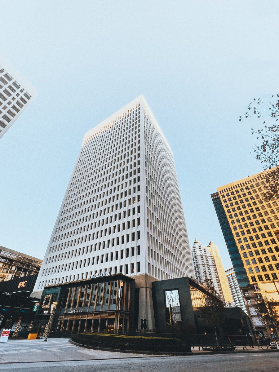 A white modernist office tower seen from the pavement against a clear winter sky.