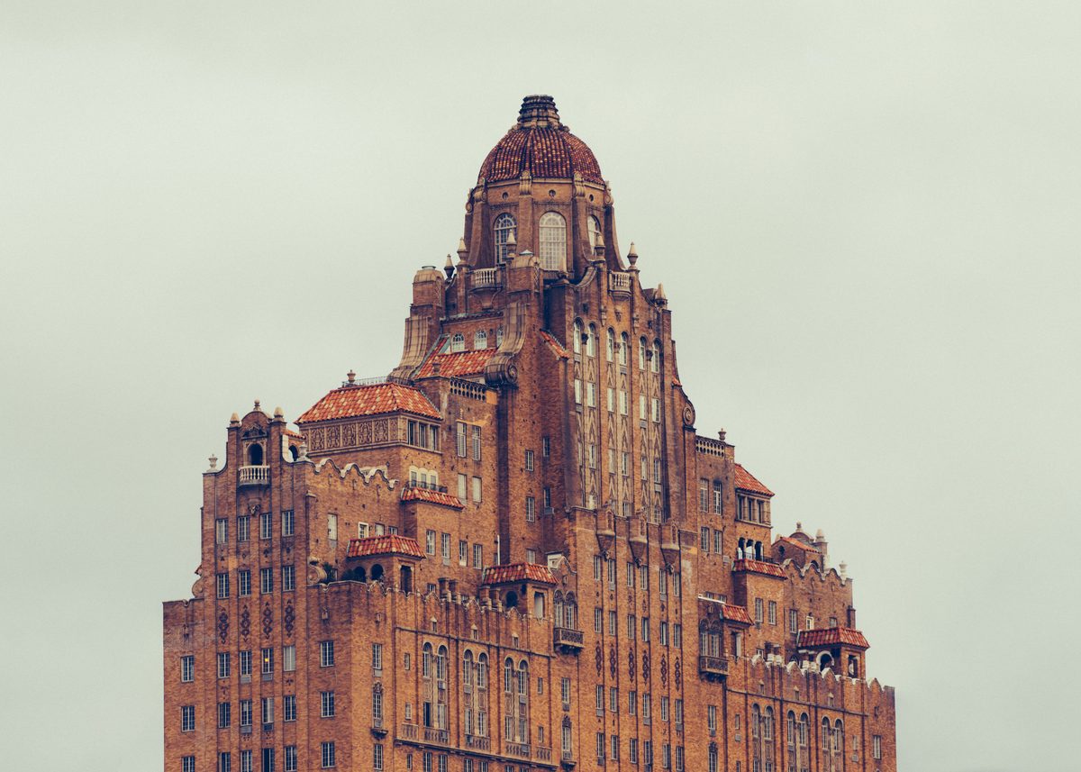 The ornate brick and terracotta crown of an old high-rise against a blank grey sky.