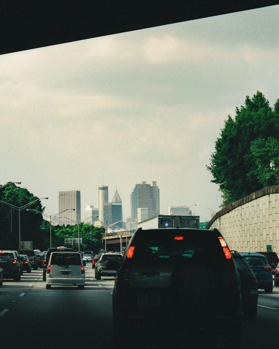 Traffic ahead on the interstate through a windscreen, a hazy skyline on the horizon.