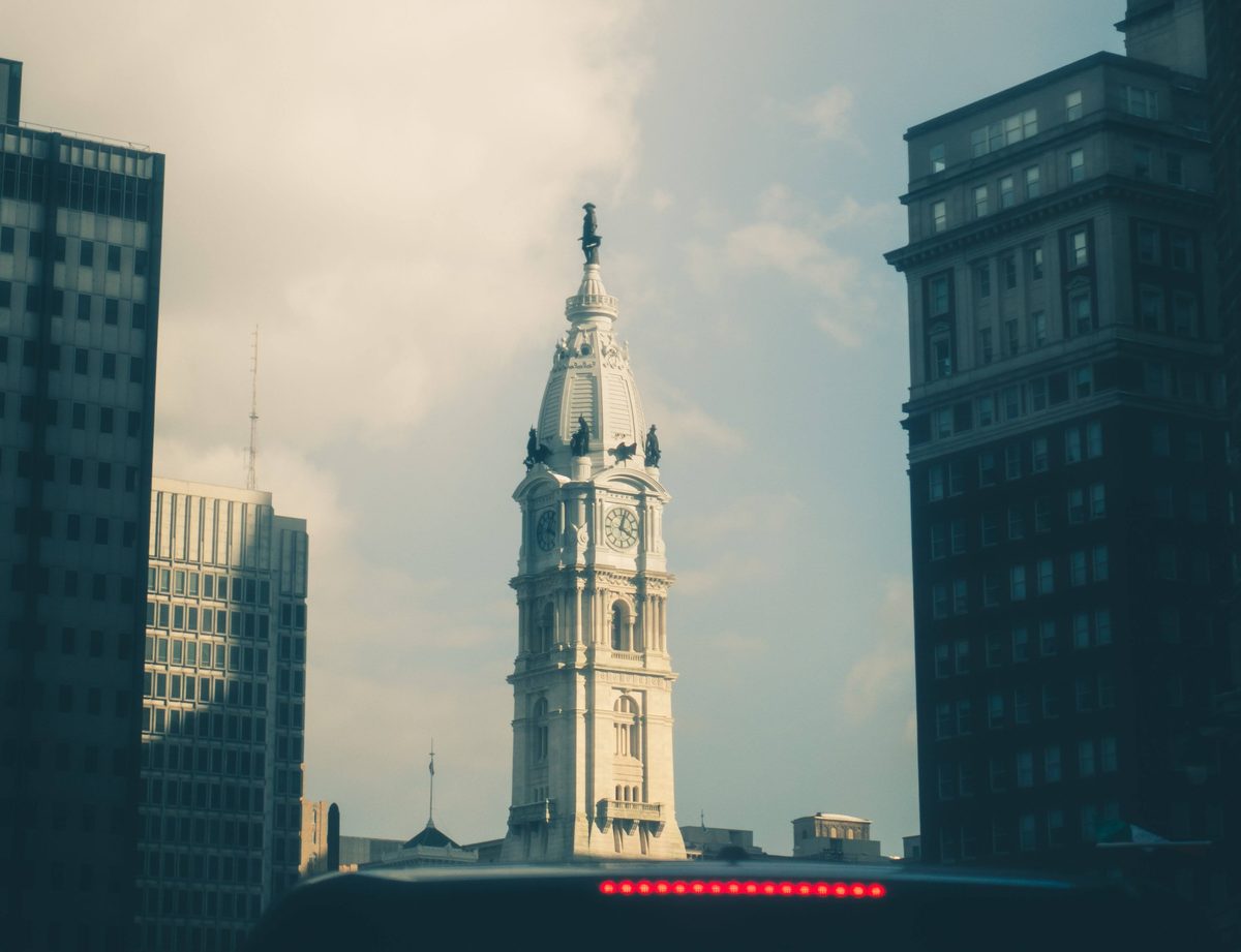 Philadelphia City Hall framed between two towers, seen over a car dashboard.