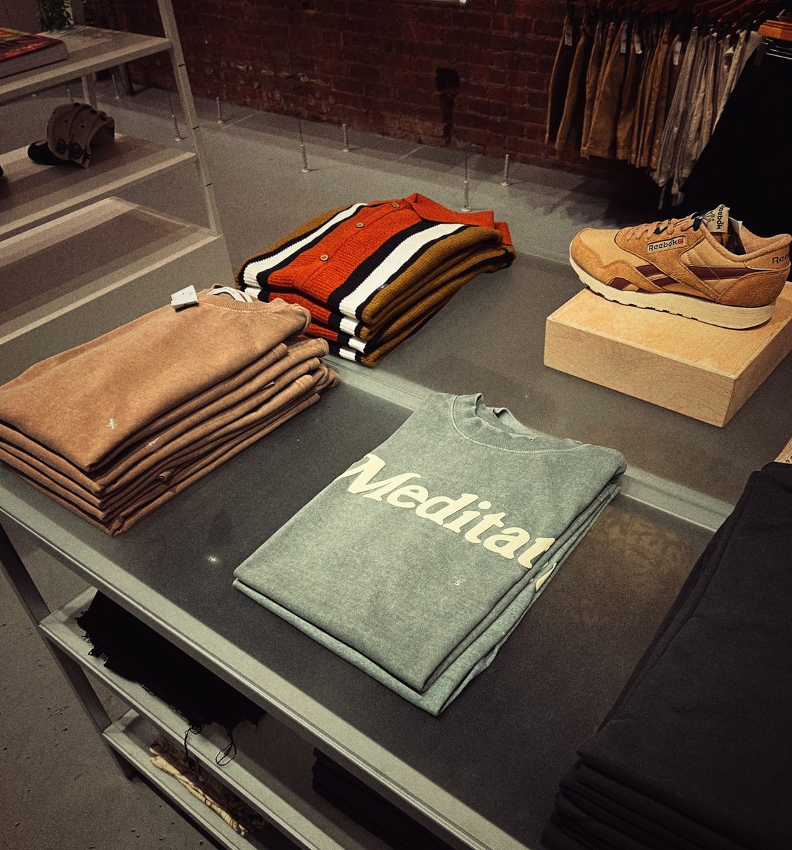 Folded sweatshirts and a pair of Reebok trainers laid out on a shop display table.