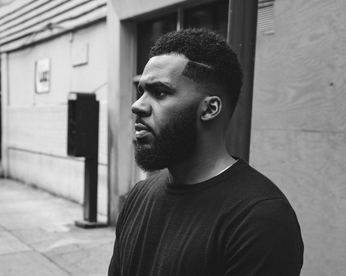 A close portrait of a man on a pavement, looking off frame, in black and white.