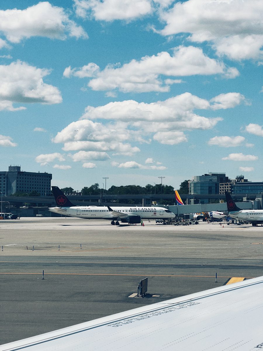 Airliners on the apron seen past a wingtip, cumulus stacked above the terminal.