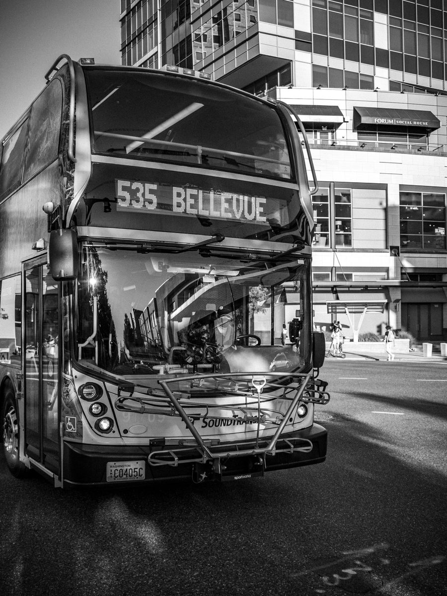 A double-decker bus signed 535 Bellevue waiting at a downtown kerb, in black and white.