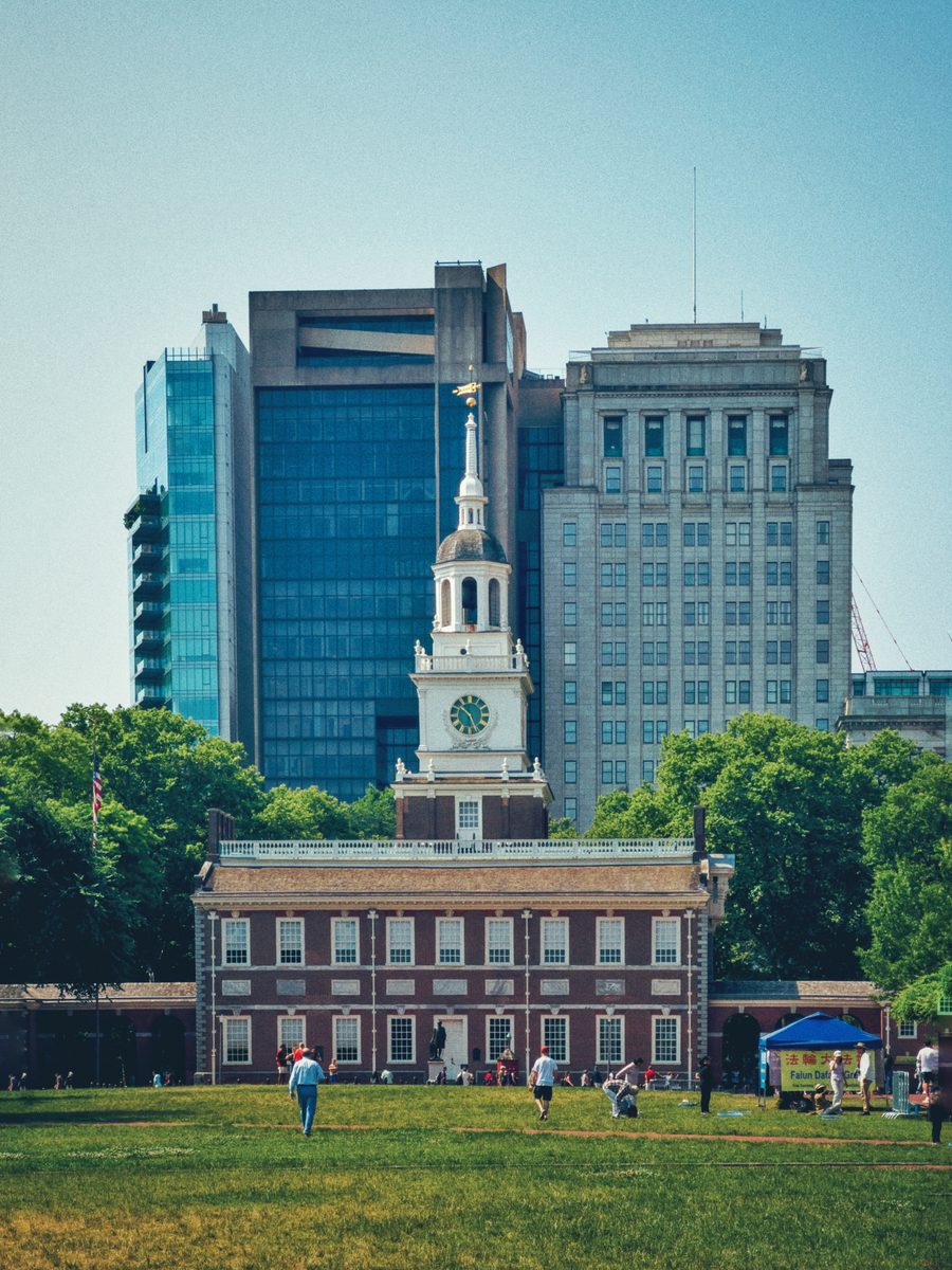 Independence Hall on its lawn with modern towers rising directly behind it in summer.
